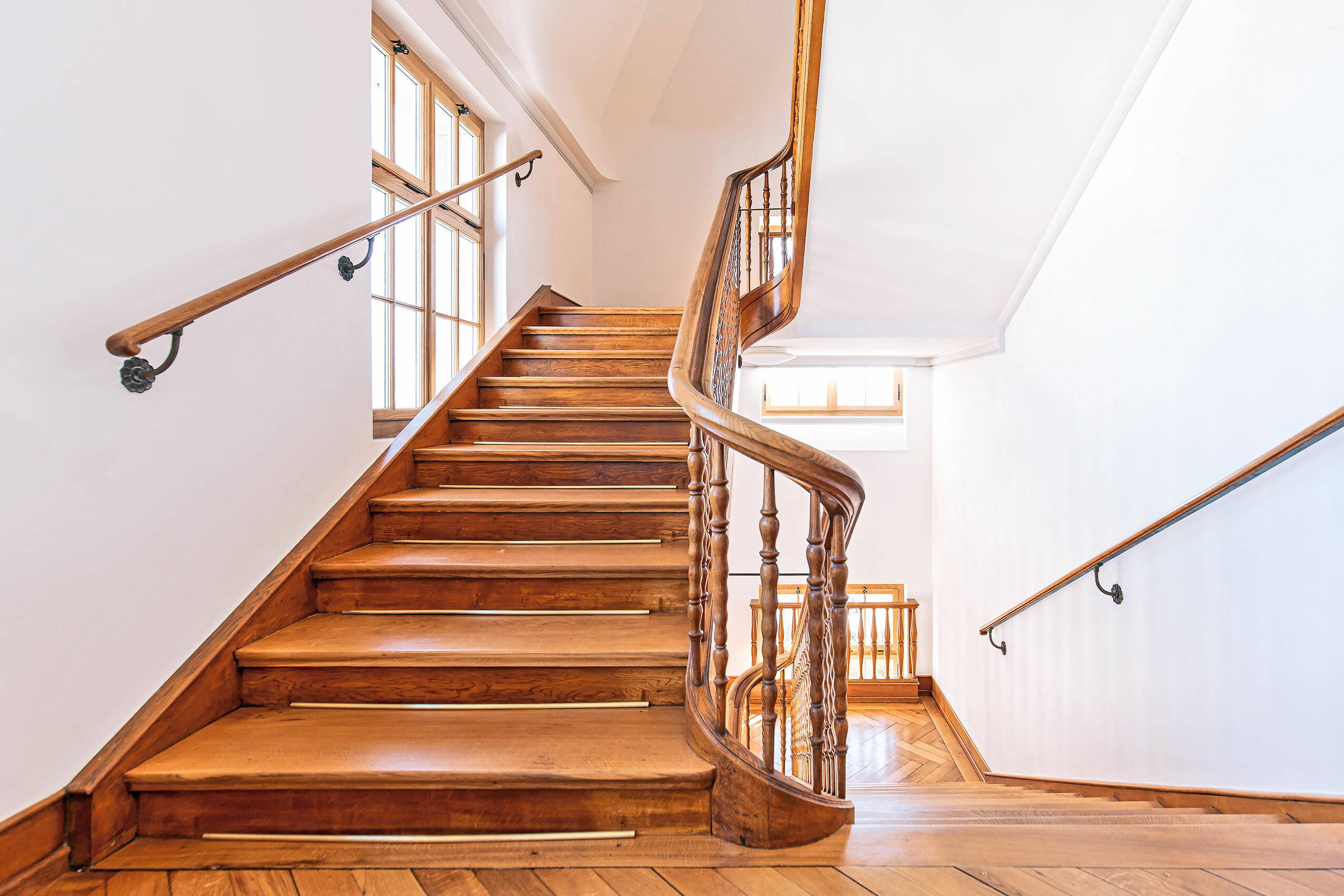 Zoom: Treppenhaus in einem Altbau mit Treppen und Geländer aus Holz.