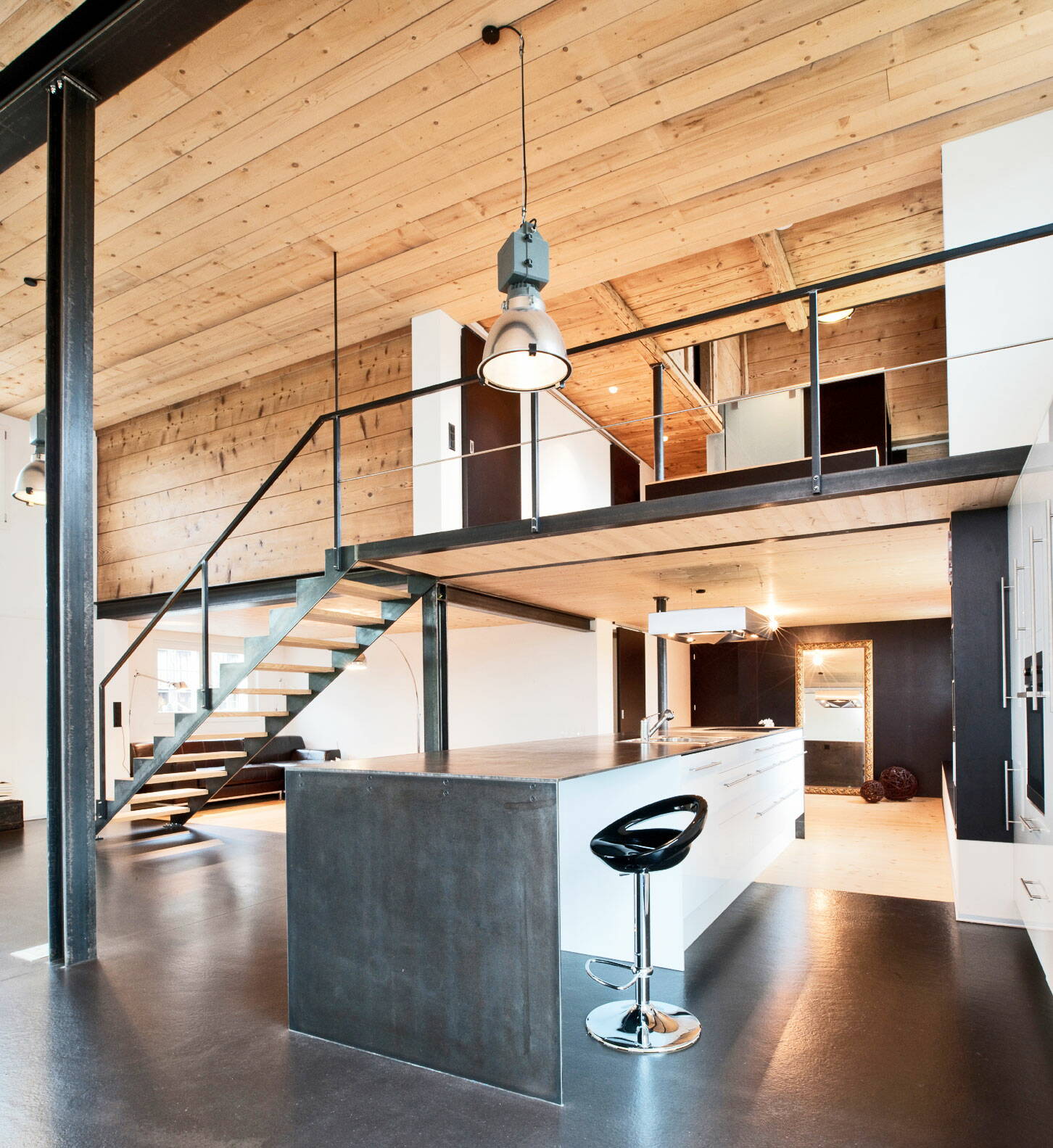 Sicht in eine Wohnküche eines Altbaus mit Wänden und Decke aus Holz sowie Küchen- und Konstruktionselementen aus Metall.