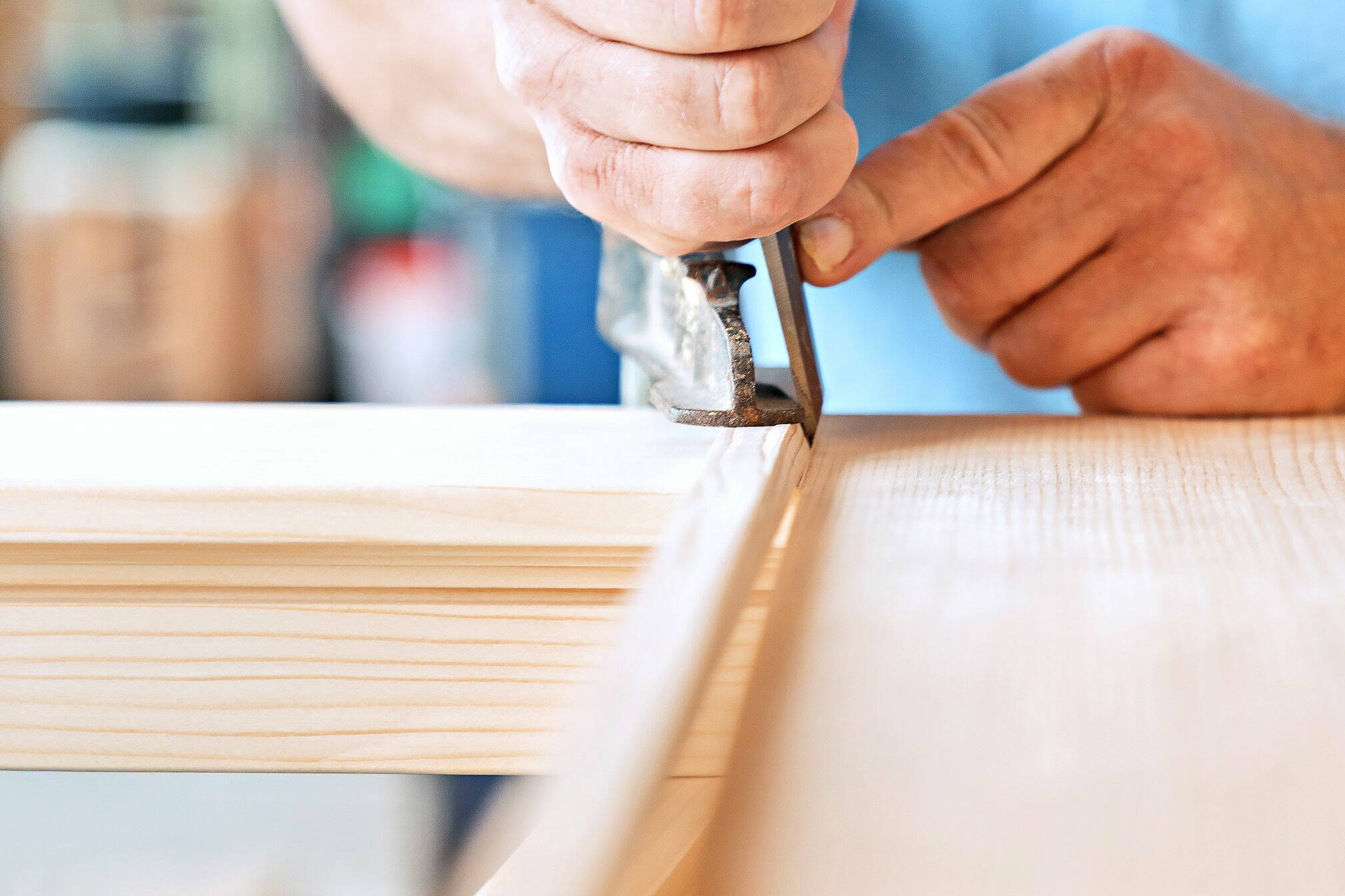 Fensterbauer bearbeitet mit einem Werkzeug einen Fensterrahmen aus Holz.