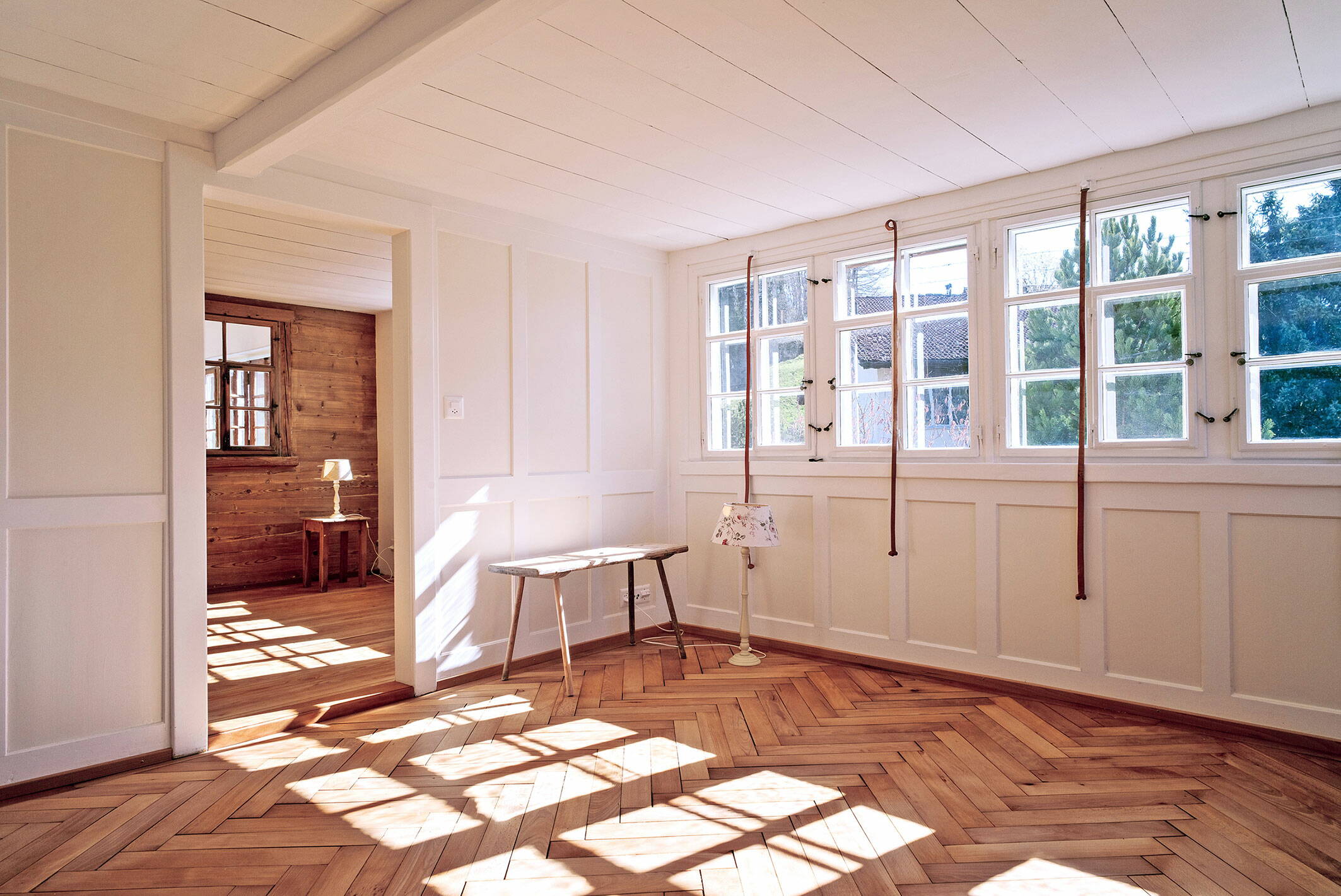 Sicht auf eine an der Decke befestigten, über dem Boden schwebenden Treppe aus Holz in einem Altbaugebäude.