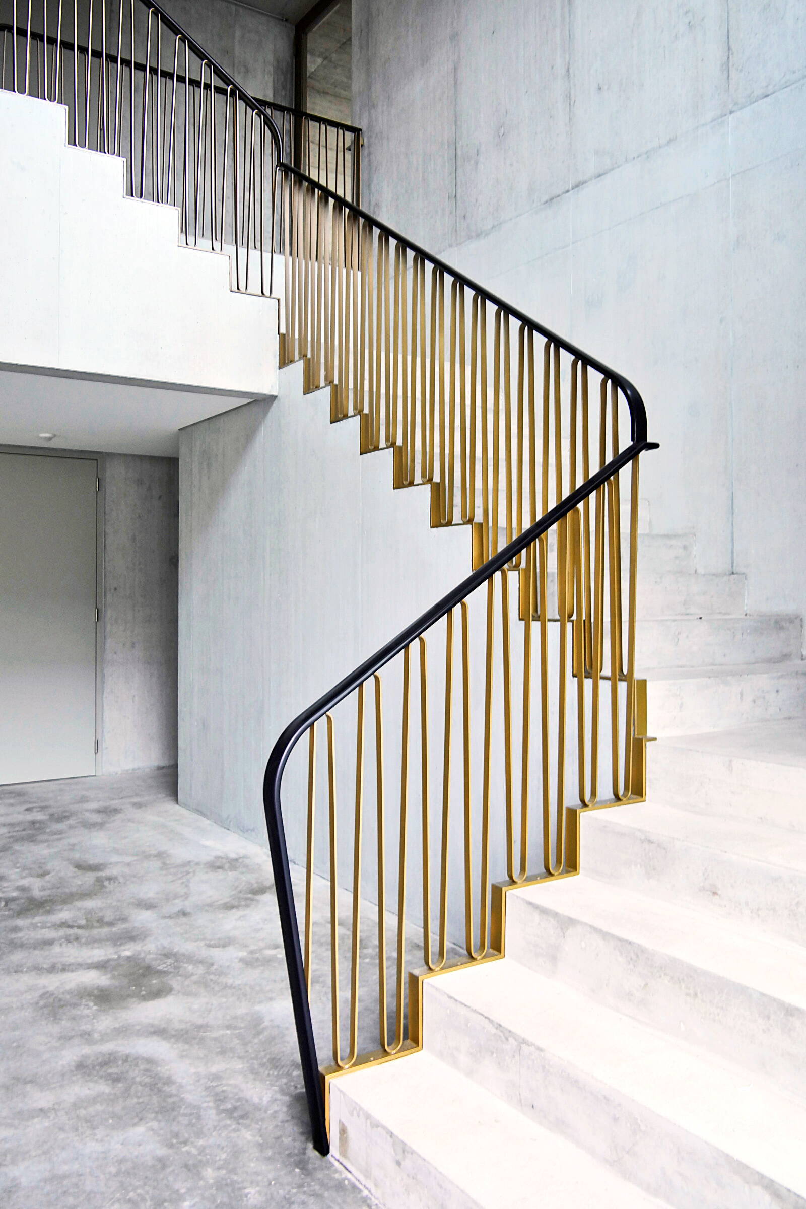 Sicht auf eine Betontreppe mit Metallgeländer in einem hohen Raum.